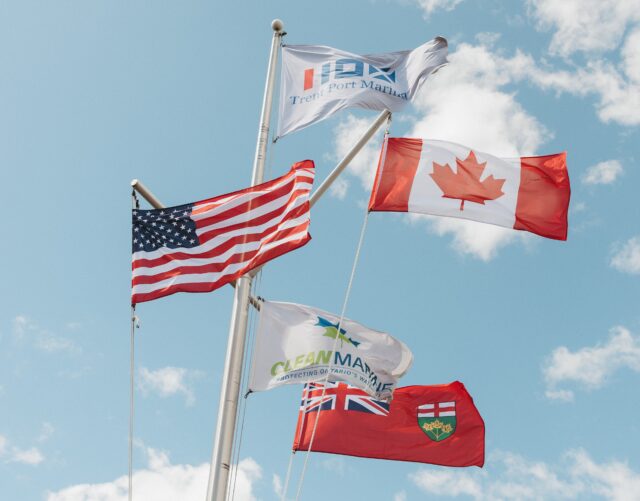 Flags, including the Clean Marine flag, displayed in front of a blue sky with clouds at Trent Port Marina
